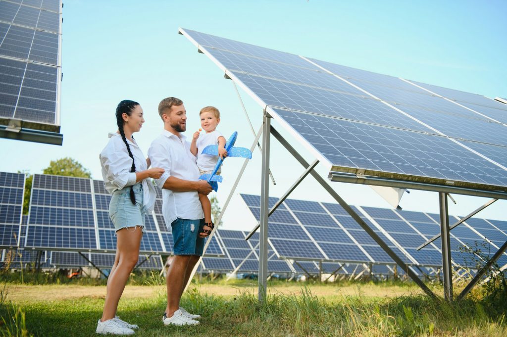 Young family with a small child in her arms on a background of solar panels.